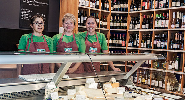 Foto der Käsetheke am Standort Sinzheim hinter der Theke stehen 3 Mitarbeiterinnen und laecheln in die Kamera